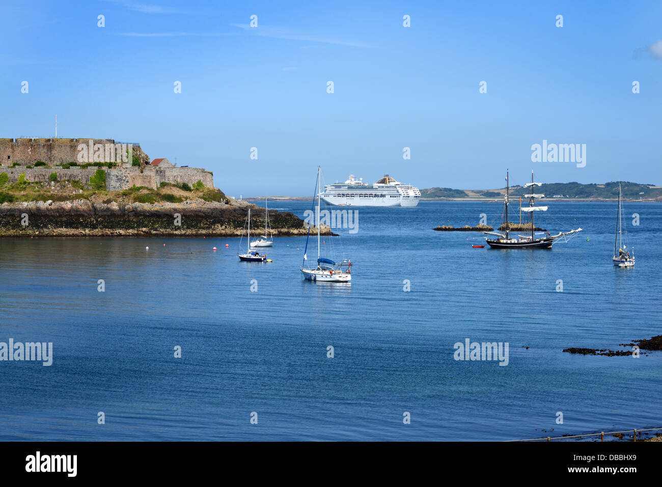 Boote in Havelet Bay übersehen von Castle Cornet und eine Kreuzfahrt Schiff in der Ferne. St Peter Port, Guernsey Stockfoto