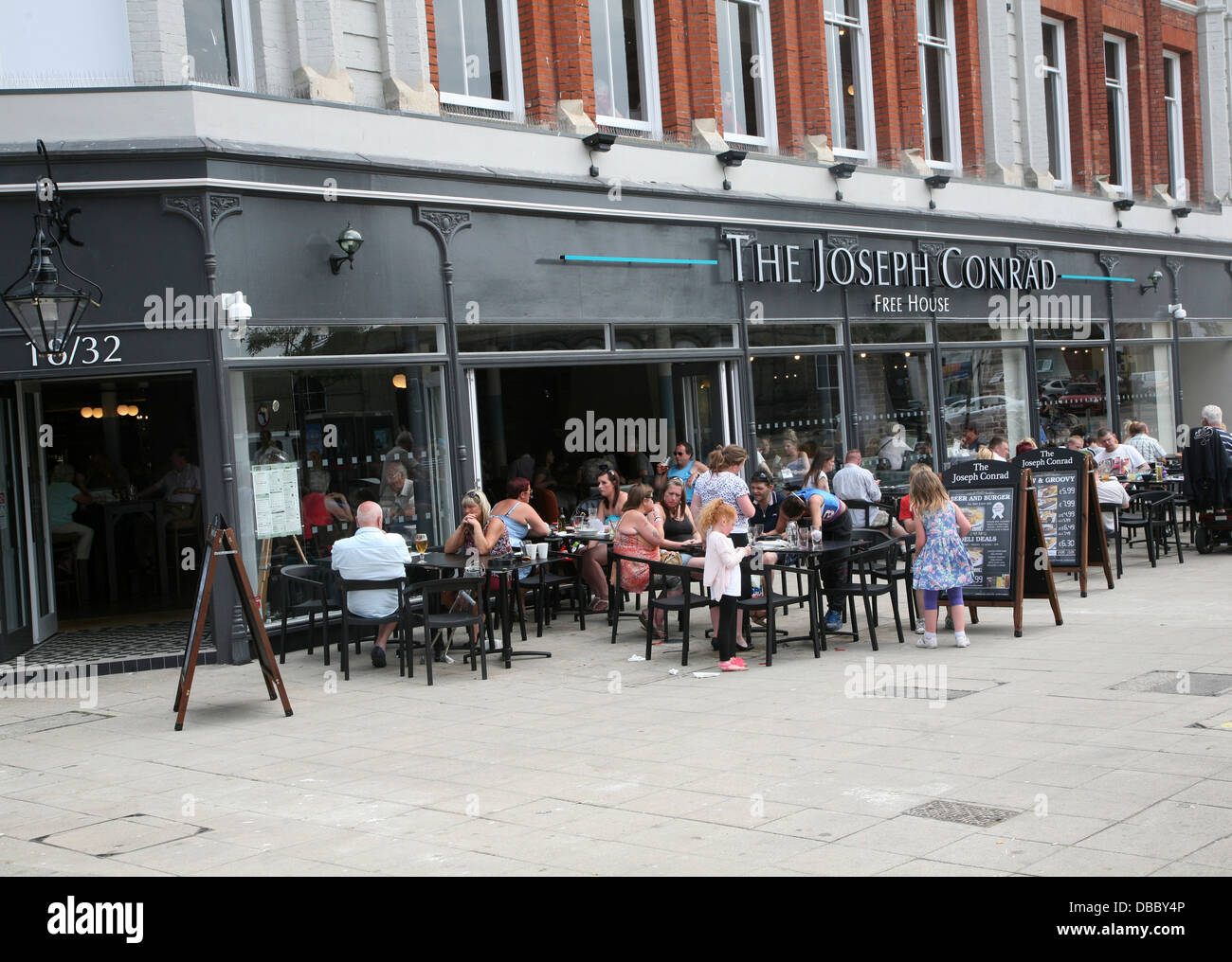 Menschen sitzen vor Joseph Conrad Wetherspoons Pub Lowestoft Suffolk England in umgebauten Ladenbau Stockfoto
