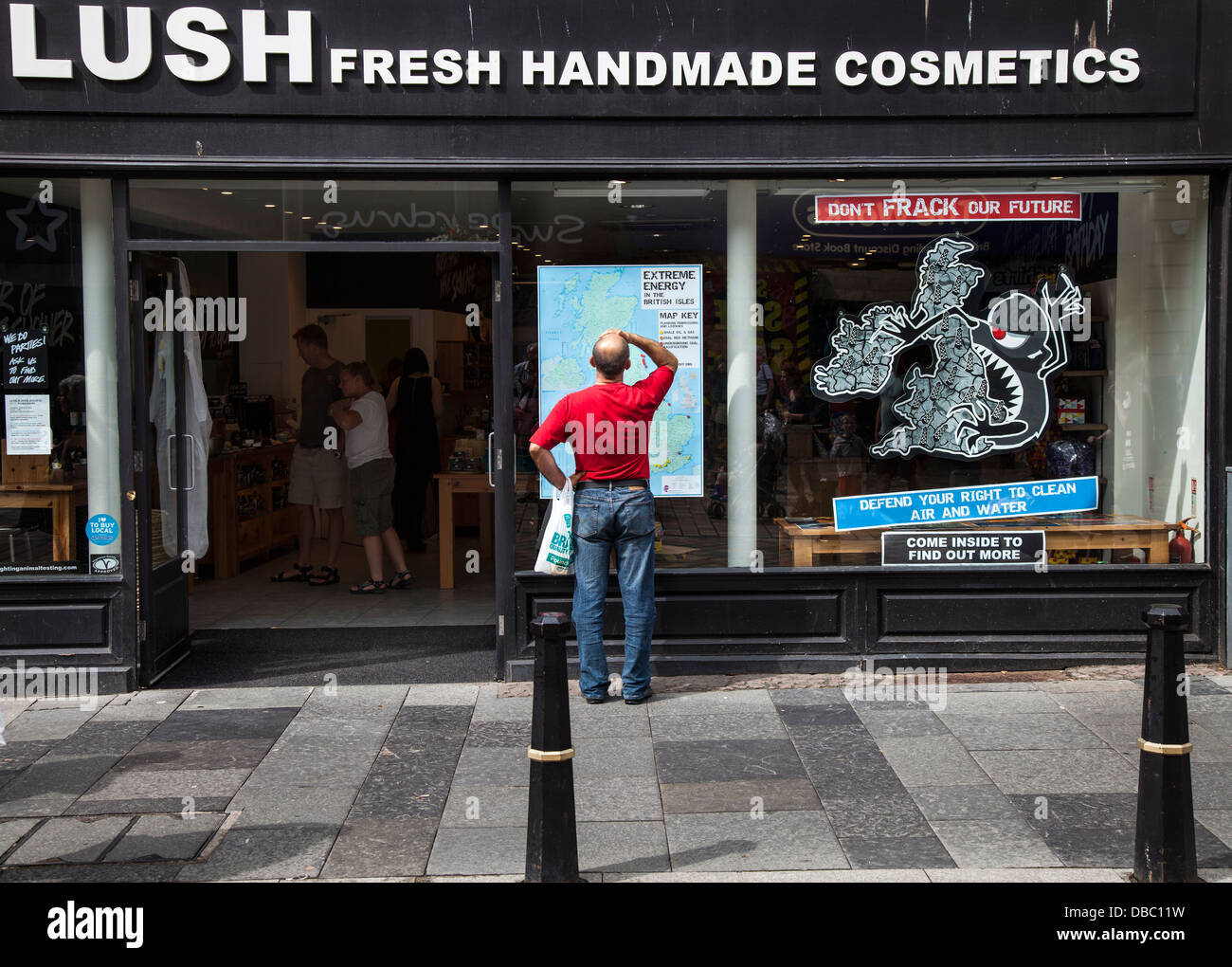 Mann auf der Suche auf Karte von Uk Lush Kosmetik Window Shops und Gebäude des Inverness High Street, Schottland, UK Stockfoto