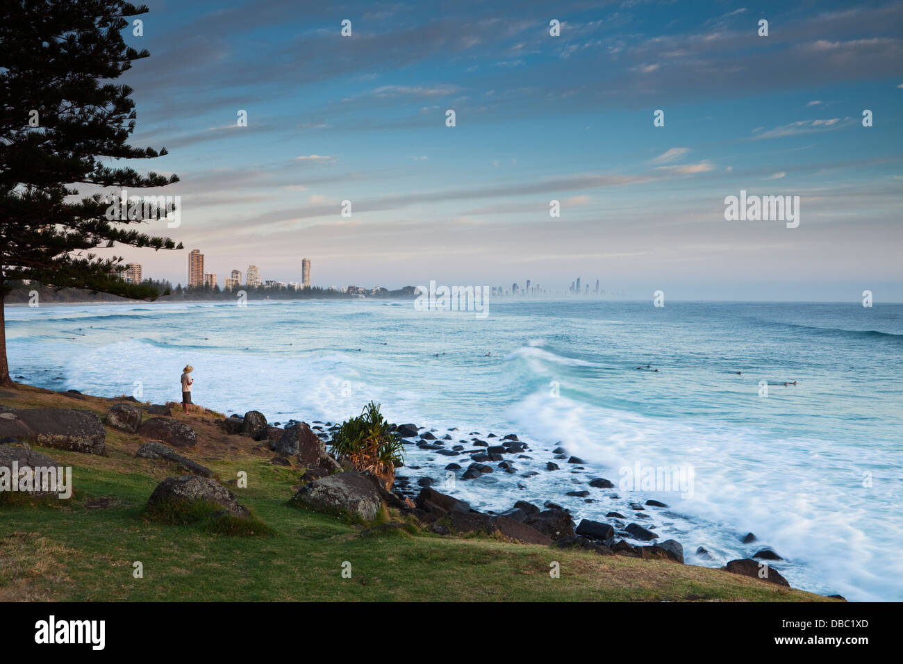 Mann, die Surfer bei Burley Heads, bei Sonnenaufgang zu beobachten. Gold Coast, Queensland, Australien Stockfoto