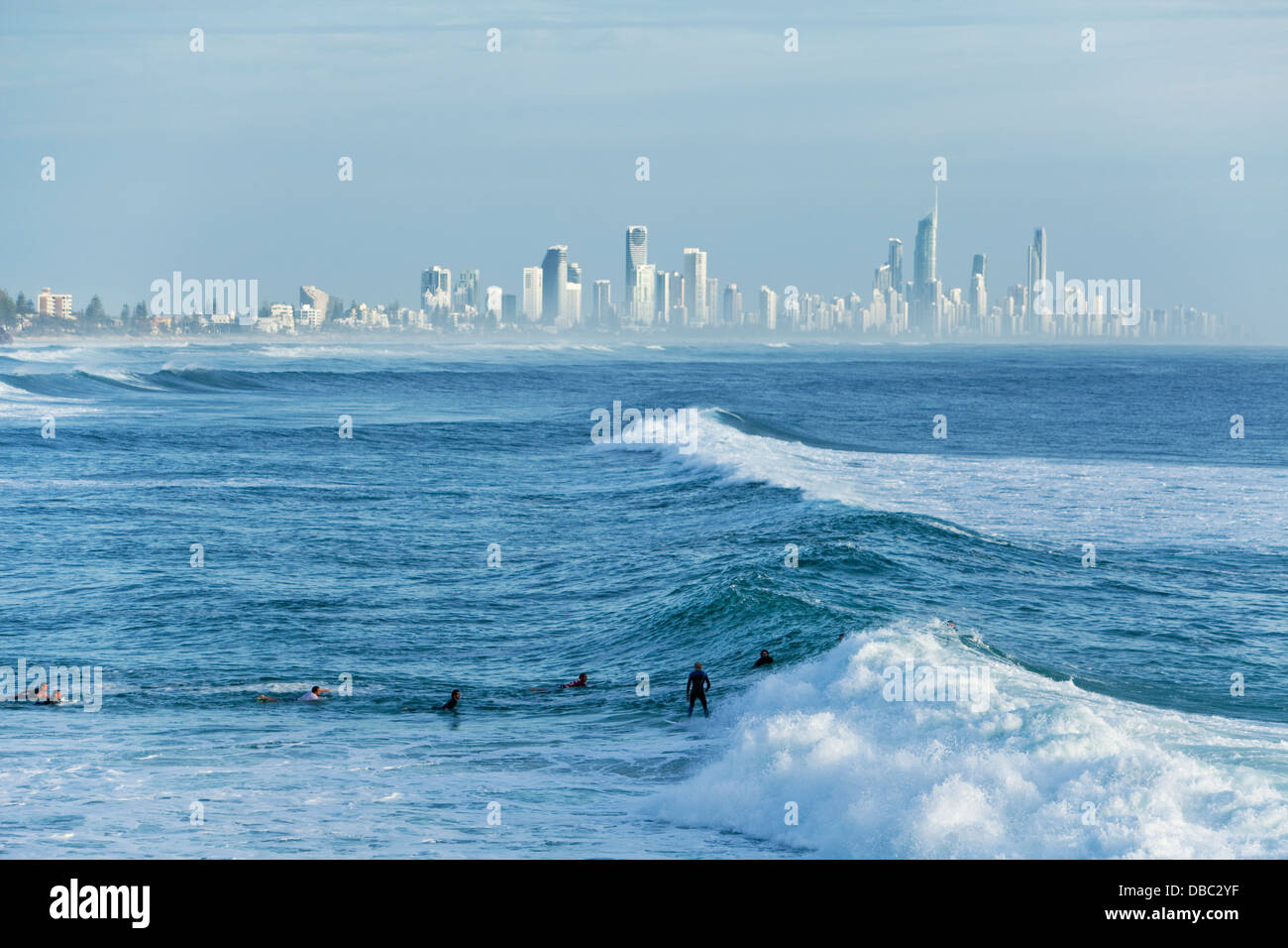 Surfer reiten Welle mit Surfers Paradise Skyline im Hintergrund. Burleigh Heads, Gold Coast, Queensland, Australien Stockfoto