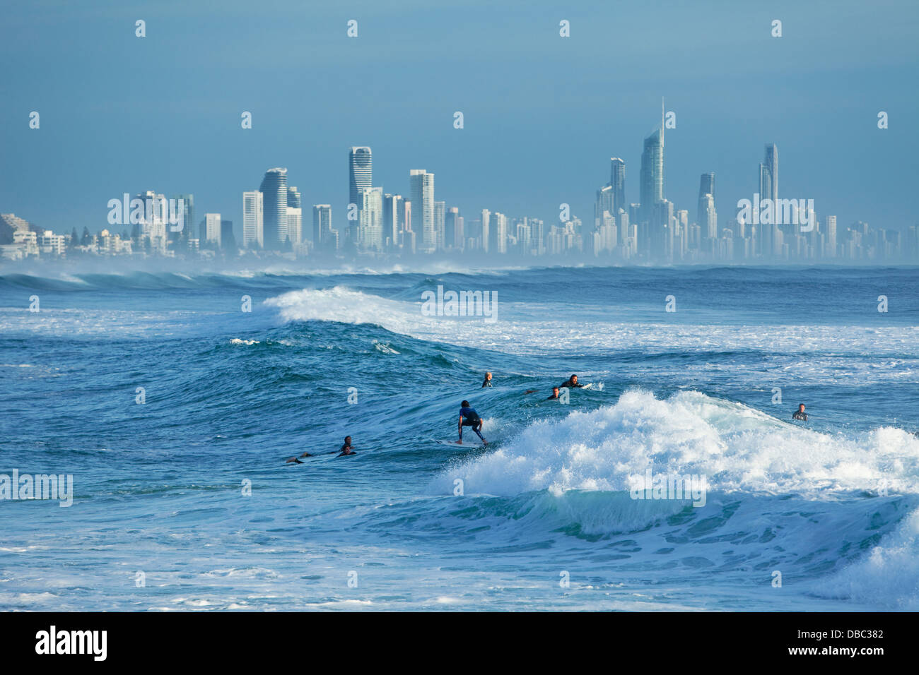 Surfer reiten Welle mit Surfers Paradise Skyline im Hintergrund. Burleigh Heads, Gold Coast, Queensland, Australien Stockfoto
