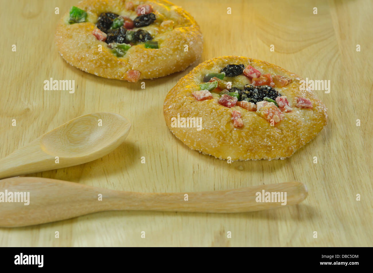 süßes Brot mit Zucker, Rosinen und getrocknete Früchte und Holzlöffel auf Holzbrett Stockfoto