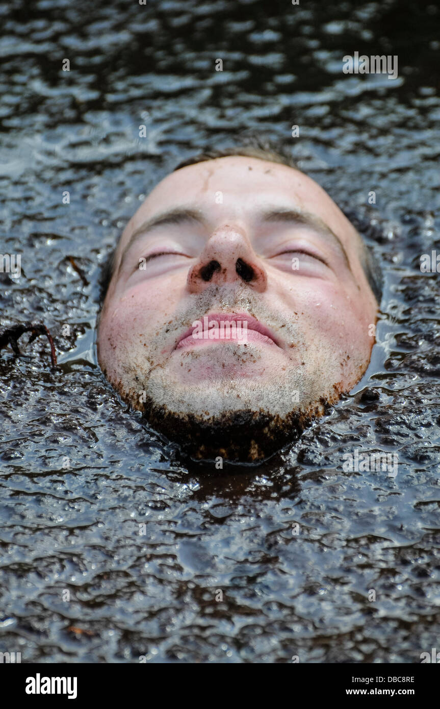 Dungannon, Nordirland, 28. Juli 2013 - ein Mann liegt unter Wasser im Schlamm mit nur sein Gesicht zeigt Credit: Stephen Barnes/Alamy Live News Stockfoto