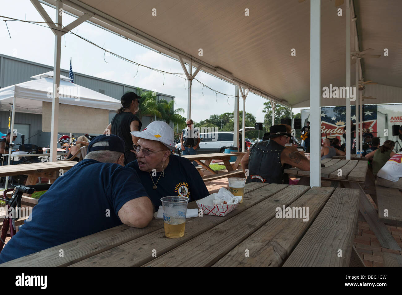 Eine Frau erzählt einem Mann ein Geheimnis während etwas zu essen zu genießen und die Teilnahme an der Gator Harley-Davidson 20. Jahrestag Partei. Stockfoto