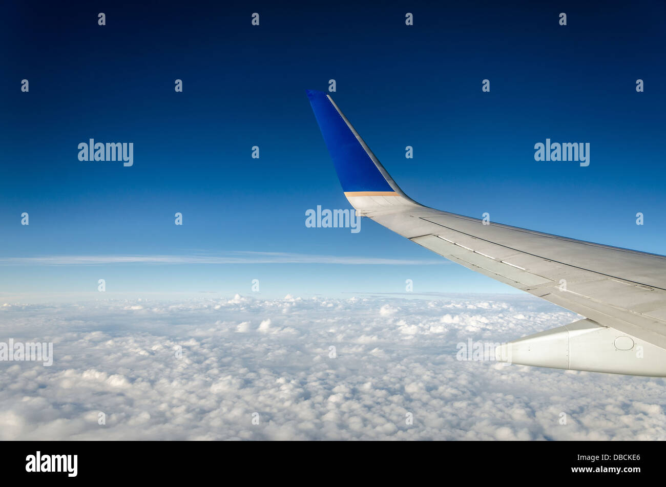 Flügel eines Flugzeugs mit schönen weißen Wolken und einem tiefblauen Himmel Stockfoto