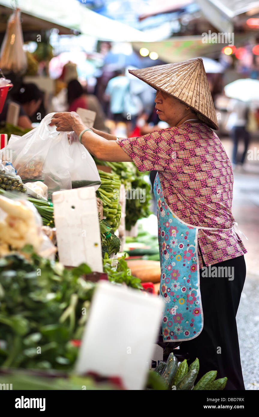 Frau in konische Hut arbeiten bei einem Gemüse Stall bei Graham Street nass Markt, Hong Kong Island Stockfoto