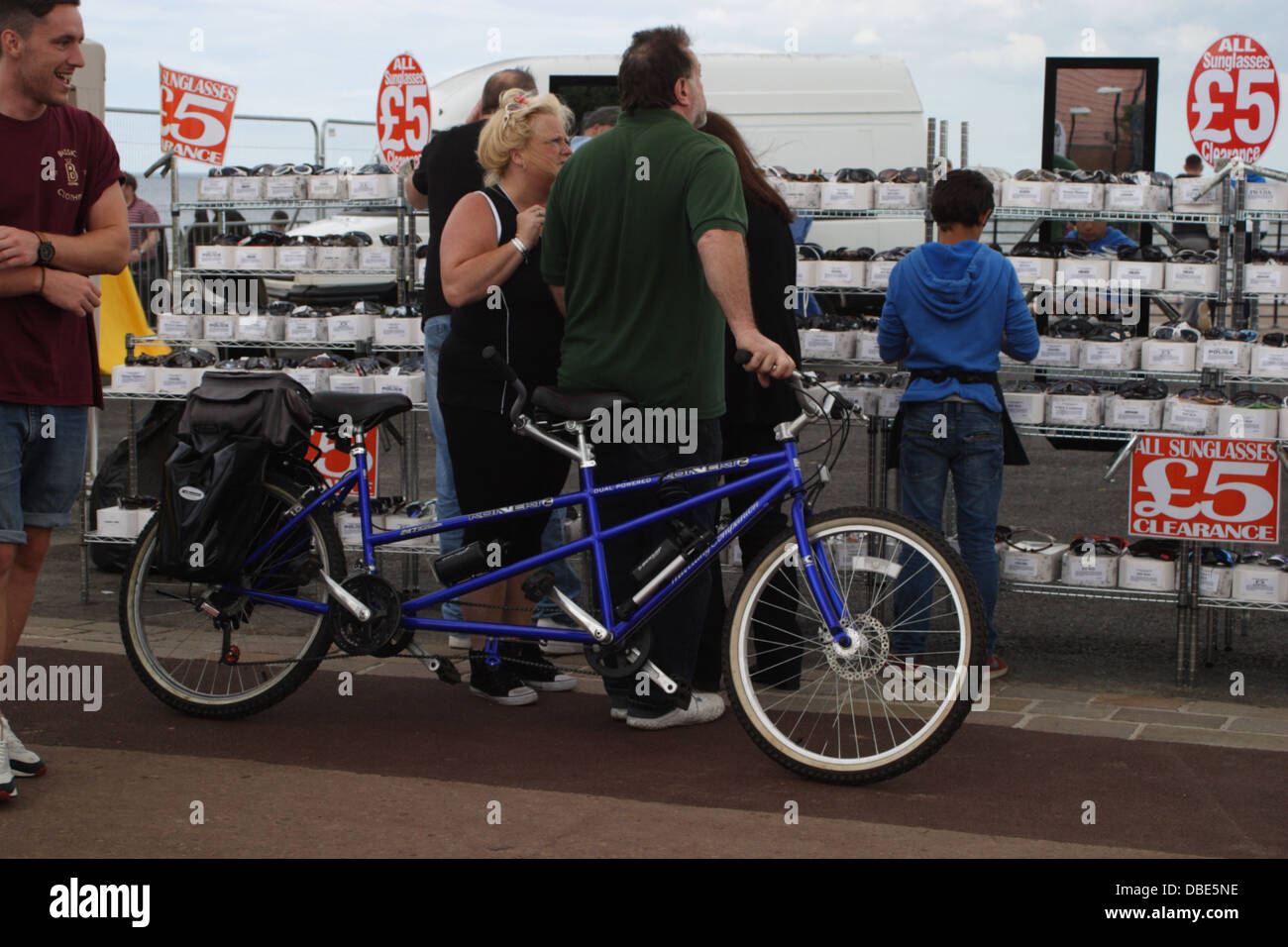 Ein Mann und eine Frau mit einem Tandem-Fahrrad stellen Sie sich vor Menschen Surfen für Sonnenbrillen auf einen Stand auf der Sunderland Airshow. Stockfoto