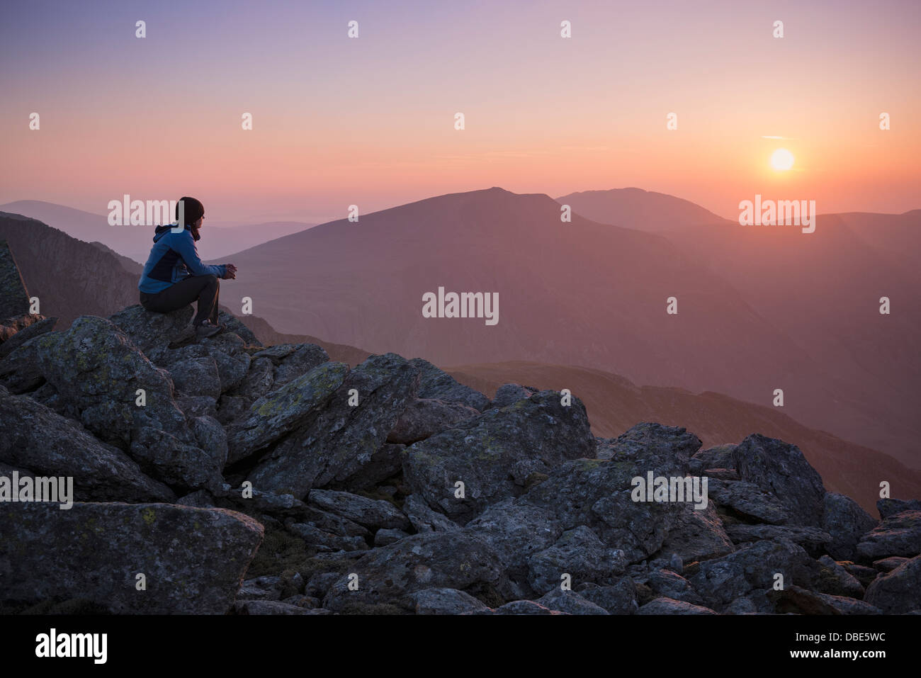 Weibliche Wanderer Uhren Sonnenuntergang über Berge vom Gipfel des Glyder Fach, Snowdonia-Nationalpark, Wales Stockfoto