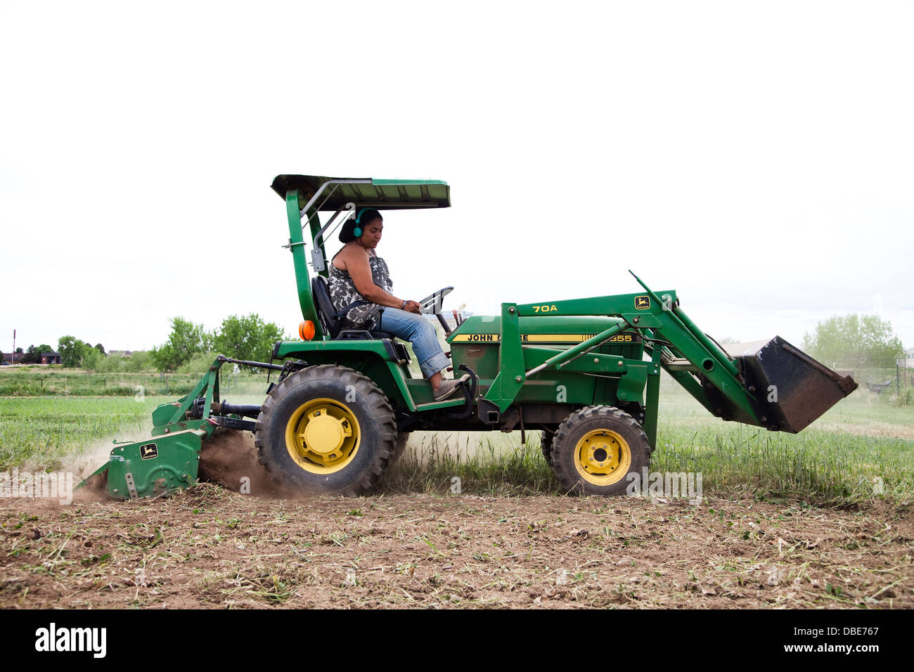 Eine Frau fährt einen Traktor in einem Feld auf ihrem urban Farm in Denver, CO. Stockfoto