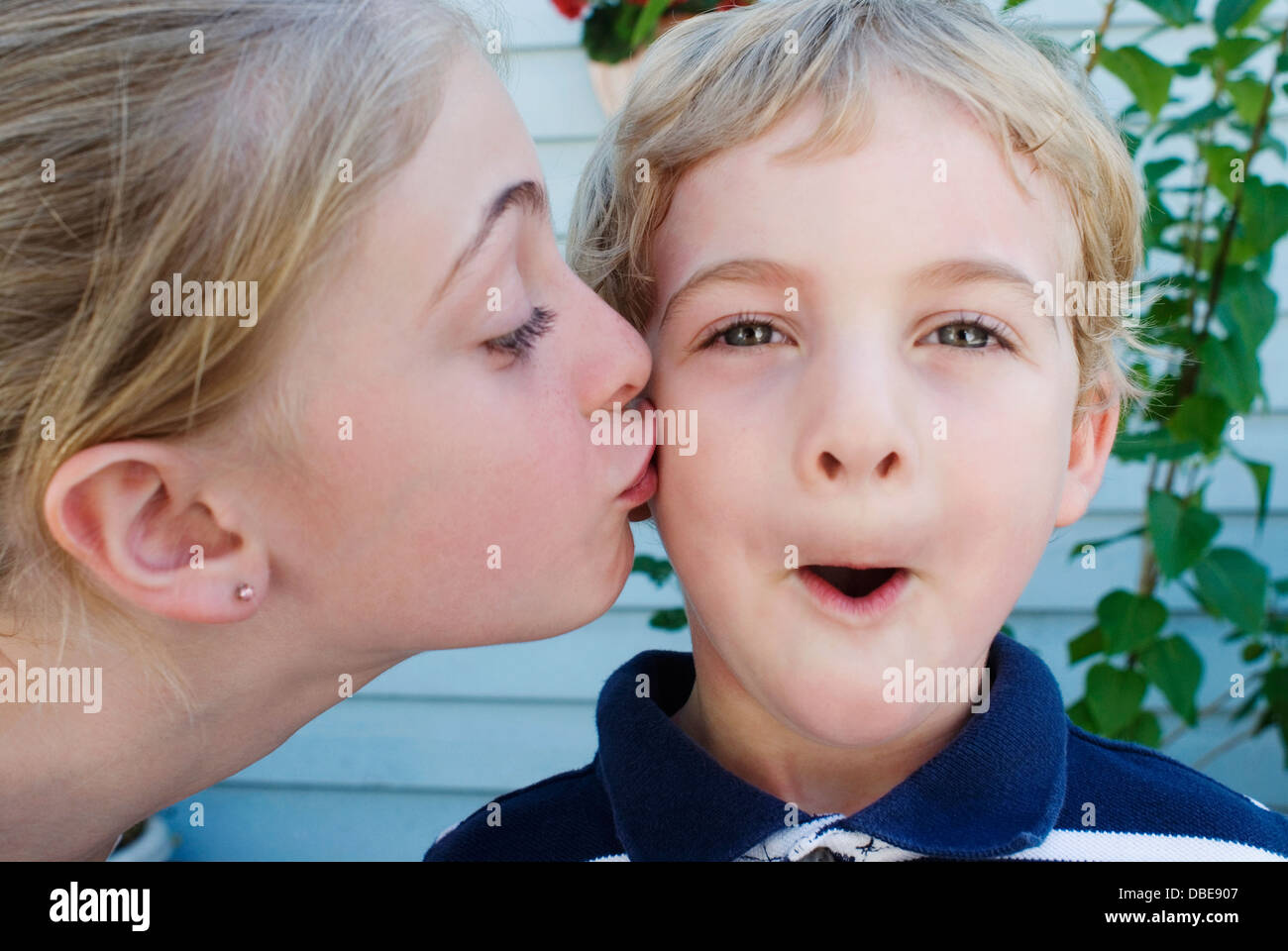 Ein junges Mädchen einen jüngeren Jungen auf die Wange küssen. Stockfoto
