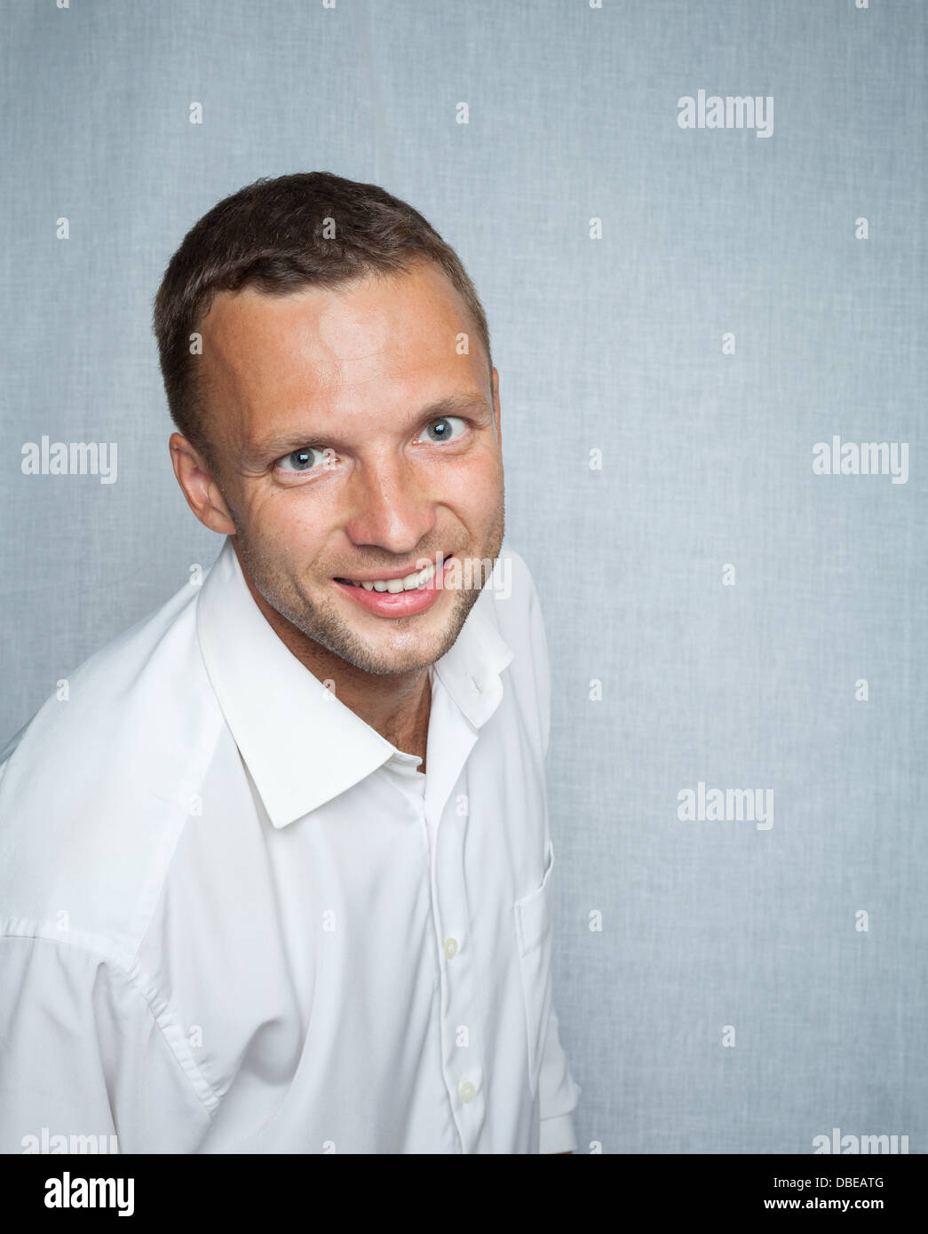 Junger lächelnder Mann im weißen Hemd über grauen Hintergrund. Studio-Porträt Stockfoto