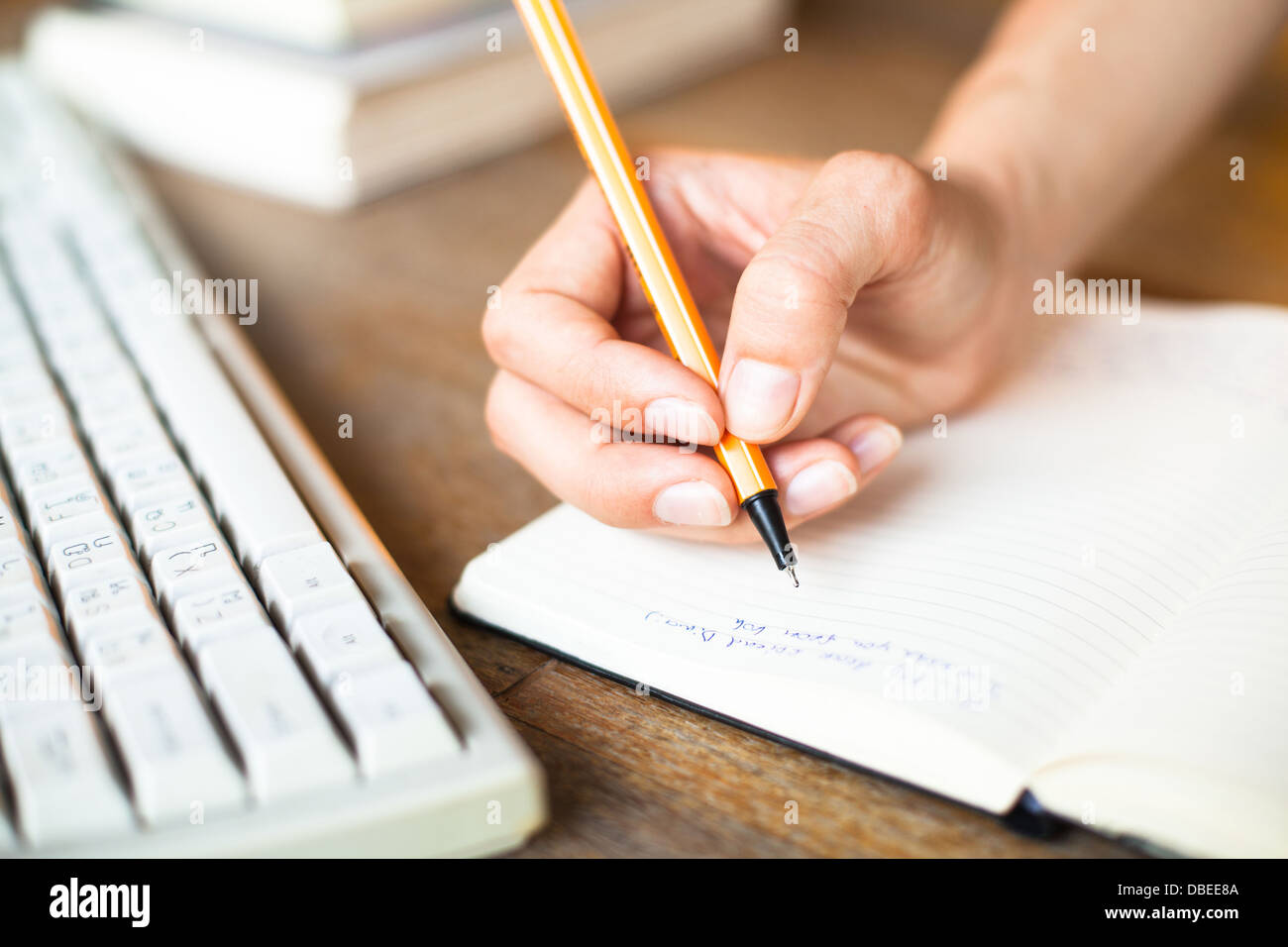 Händen schreibt einen Stift in einem Notebook, Computer-Tastatur im Hintergrund. Stockfoto