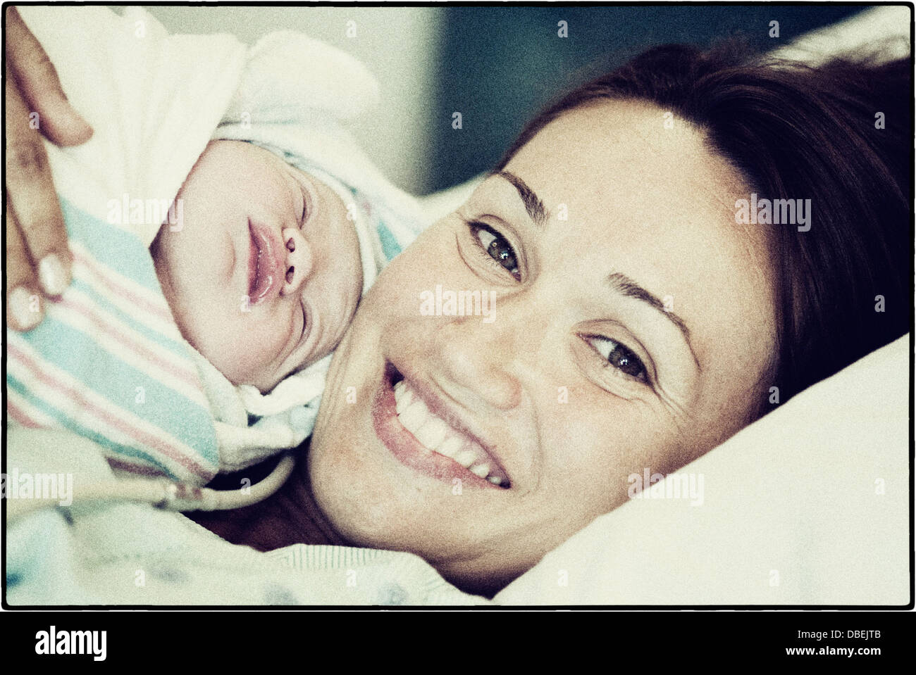 Hispanische Mutter und neugeborenes Baby im Krankenhausbett - Smartphone-aufgenommenes Stockfoto