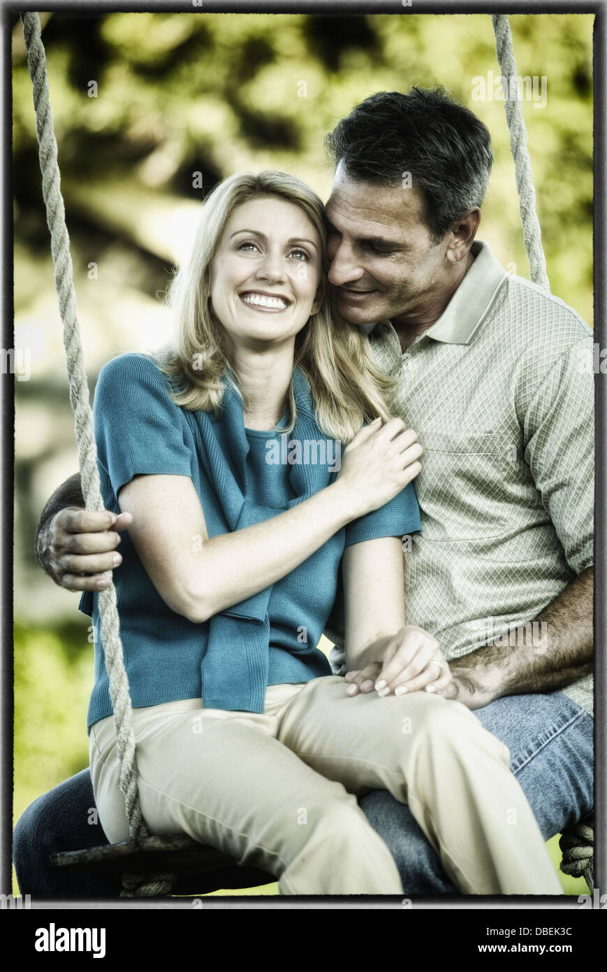 Hispanische paar Zusammensitzen auf Baum-Schaukel - Smartphone-aufgenommenes Stockfoto