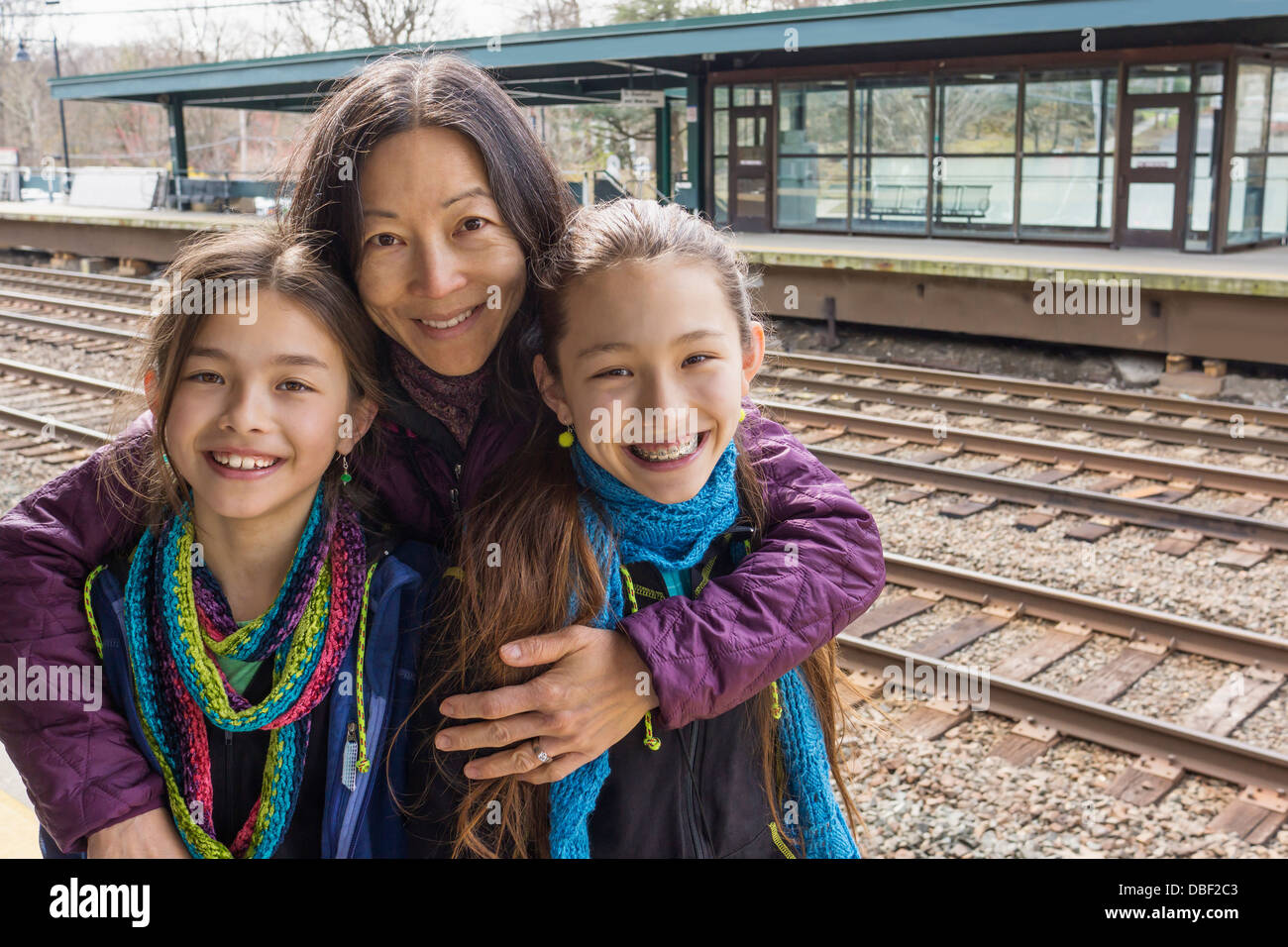 Mutter und Töchter lächelnd am Bahnhof Stockfoto