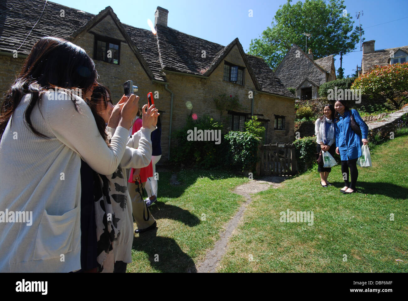 Asiatische Touristen am Arlington Row, ikonischen Zeile des 17. Jahrhunderts Cotswolds Ferienhäuser in Bibury, Vereinigtes Königreich Stockfoto