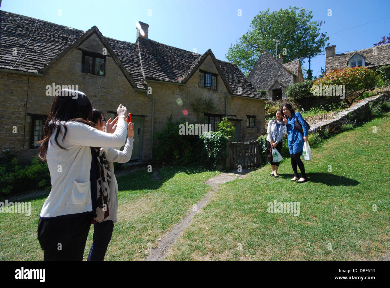 Asiatische Touristen am Arlington Row, ikonischen Zeile des 17. Jahrhunderts Cotswolds Ferienhäuser in Bibury, Vereinigtes Königreich Stockfoto