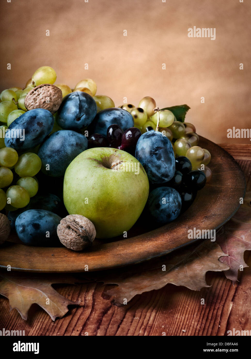 Herbstliche Früchte in Holzplatte Stockfoto