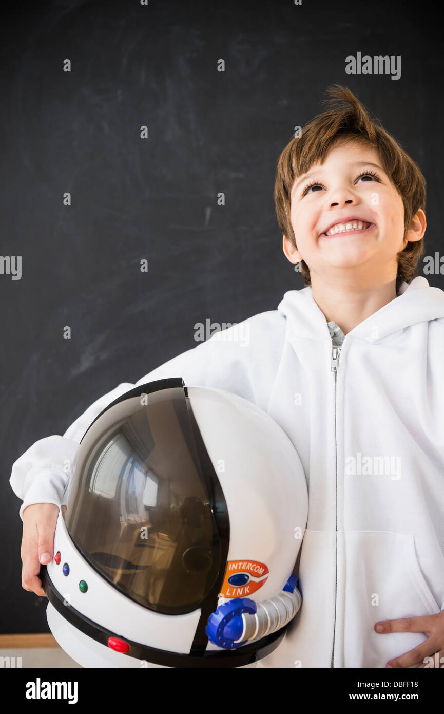 Hispanische junge hält Weltraumhelm im Klassenzimmer Stockfoto