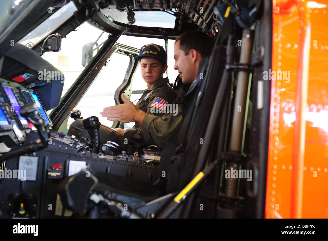 Lt. Kevin Winters, ein Air Station Kodiak MH-60 Jayhawk Helikopterpilot erklärt das Cockpit-Layout von der Jayhawk Braeden Hahn, ein Bewohner von New Jersey und angehende Küstenwache-Hubschrauber-Pilot bei Air Station Kodiak, Alaska, 24. Juli 2013. Baead Stockfoto