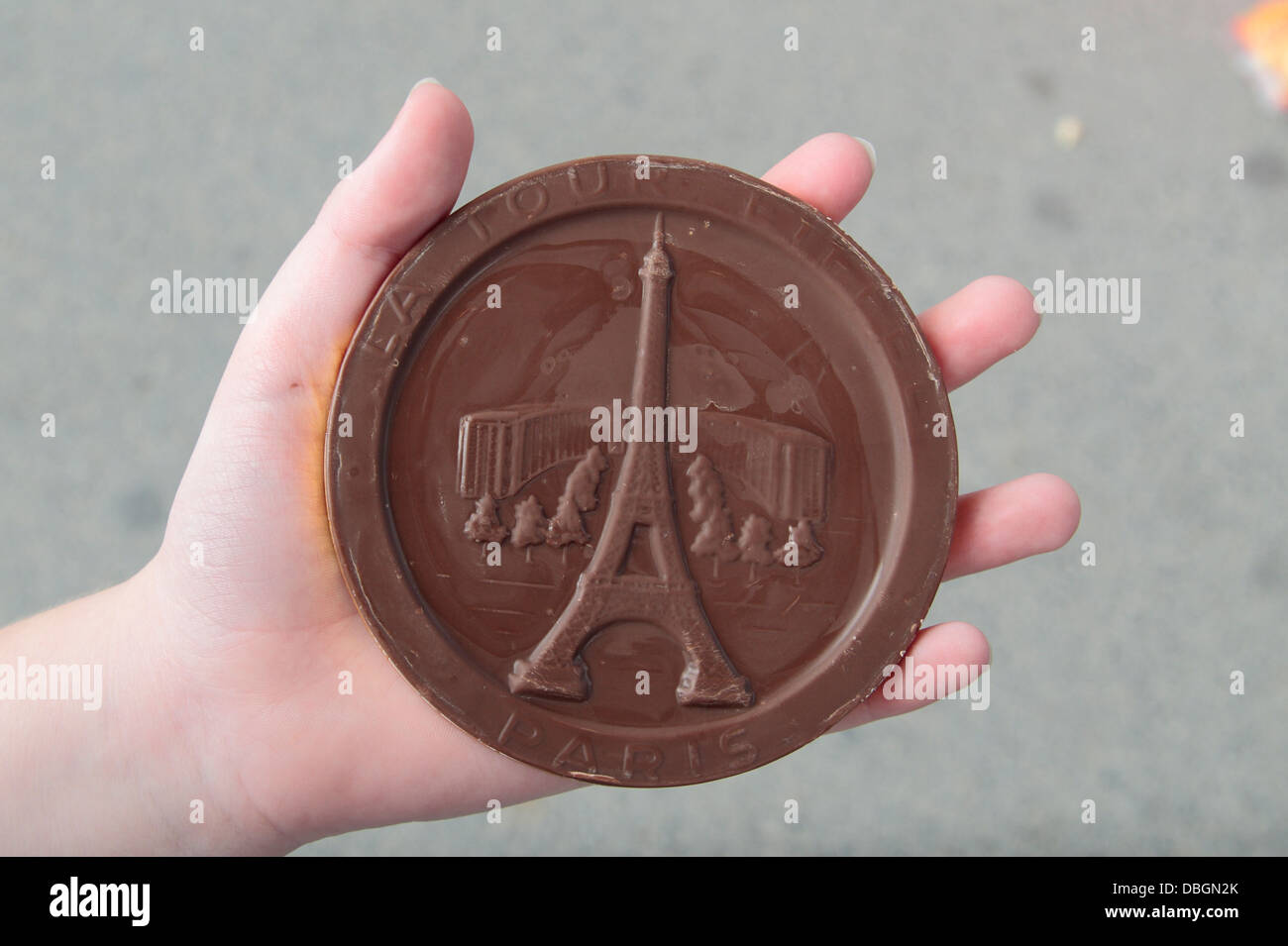 Ein Kind hält eine Souvenir Schokoladen-Münze geprägt mit dem Eiffelturm, Paris, Frankreich. Stockfoto