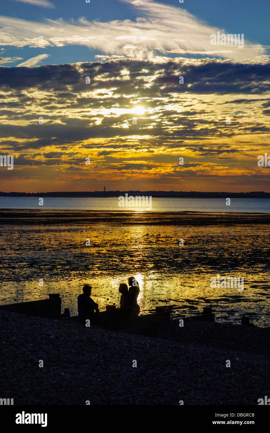 Menschen, die einen Drink bei Sonnenuntergang am Strand von Whitstable Kent Stockfoto