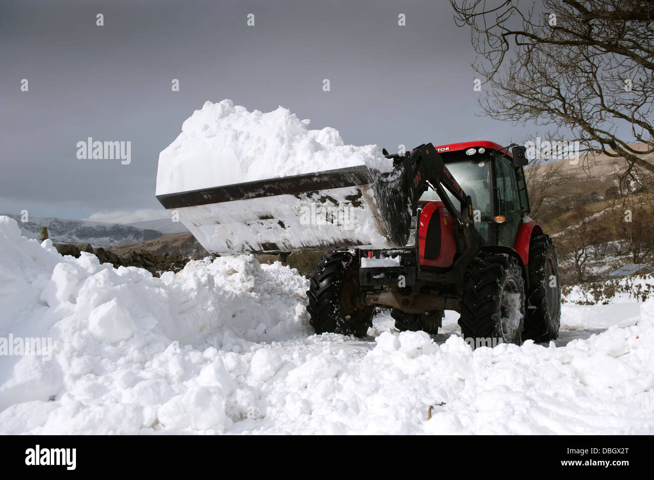 Clearing Landstraße mit Traktor und Lader nach Schneesturm es blockiert hat. Cumbria, UK. Stockfoto