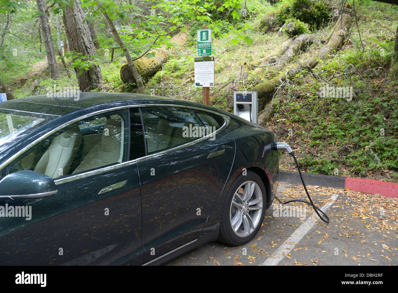 Ladestation mit einem Tesla Limousine Elektroauto eingesteckt.  Immobilienportal für details Stockfoto