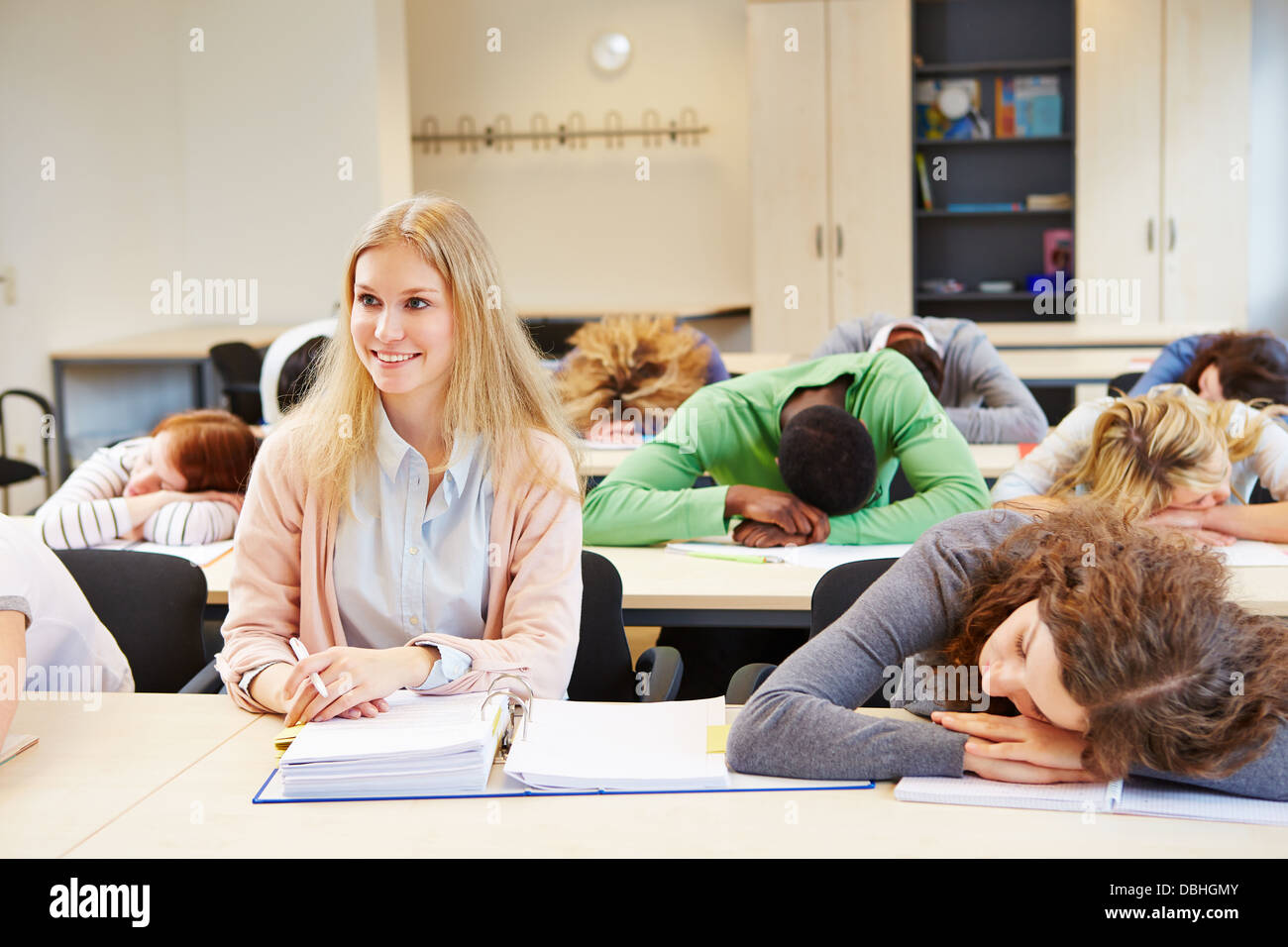 Studenten schlafen in Schule Klasse und junge Frau hält wach Stockfoto