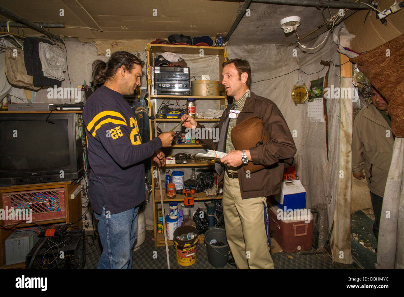 Ein lokaler Minister besucht eine mittellose militärischen Veteran in einem behelfsmäßigen Schutzraum unter Obdachlosen Einwohner Stockfoto