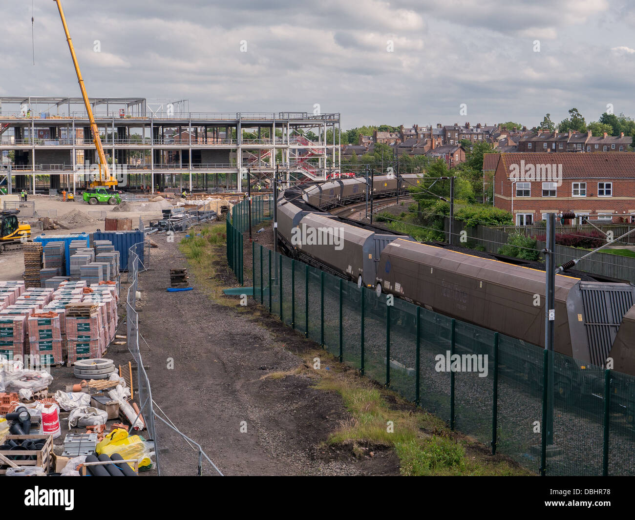 Ein Güterzug mit Kohle langsam bewegt sich zwischen einer kommerziellen Baustelle und ein Wohngebiet in York, Großbritannien. Stockfoto