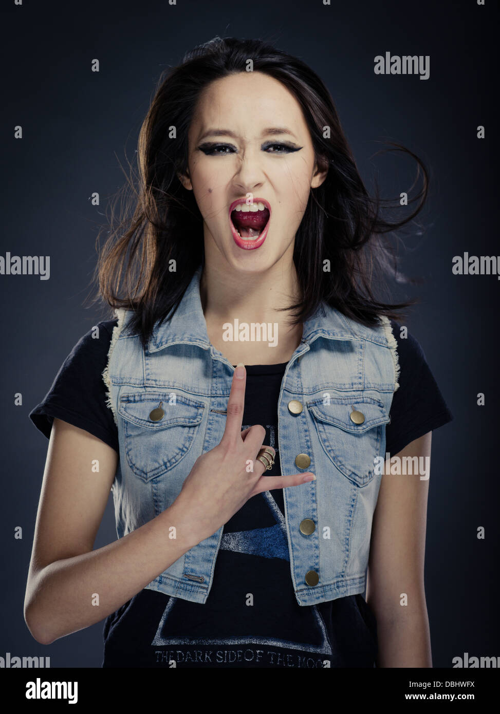 Schöne asiatische Frau mit langen, dunklen Haaren Heavy Metal Rocker Zeichen der Hörner Handgeste Stockfoto