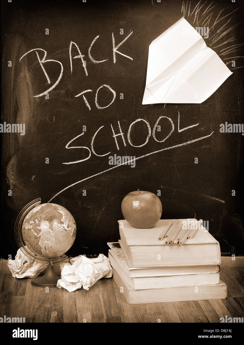 Zurück zur Schule geschrieben auf einer Tafel mit Büchern und Apfel in sepia Stockfoto