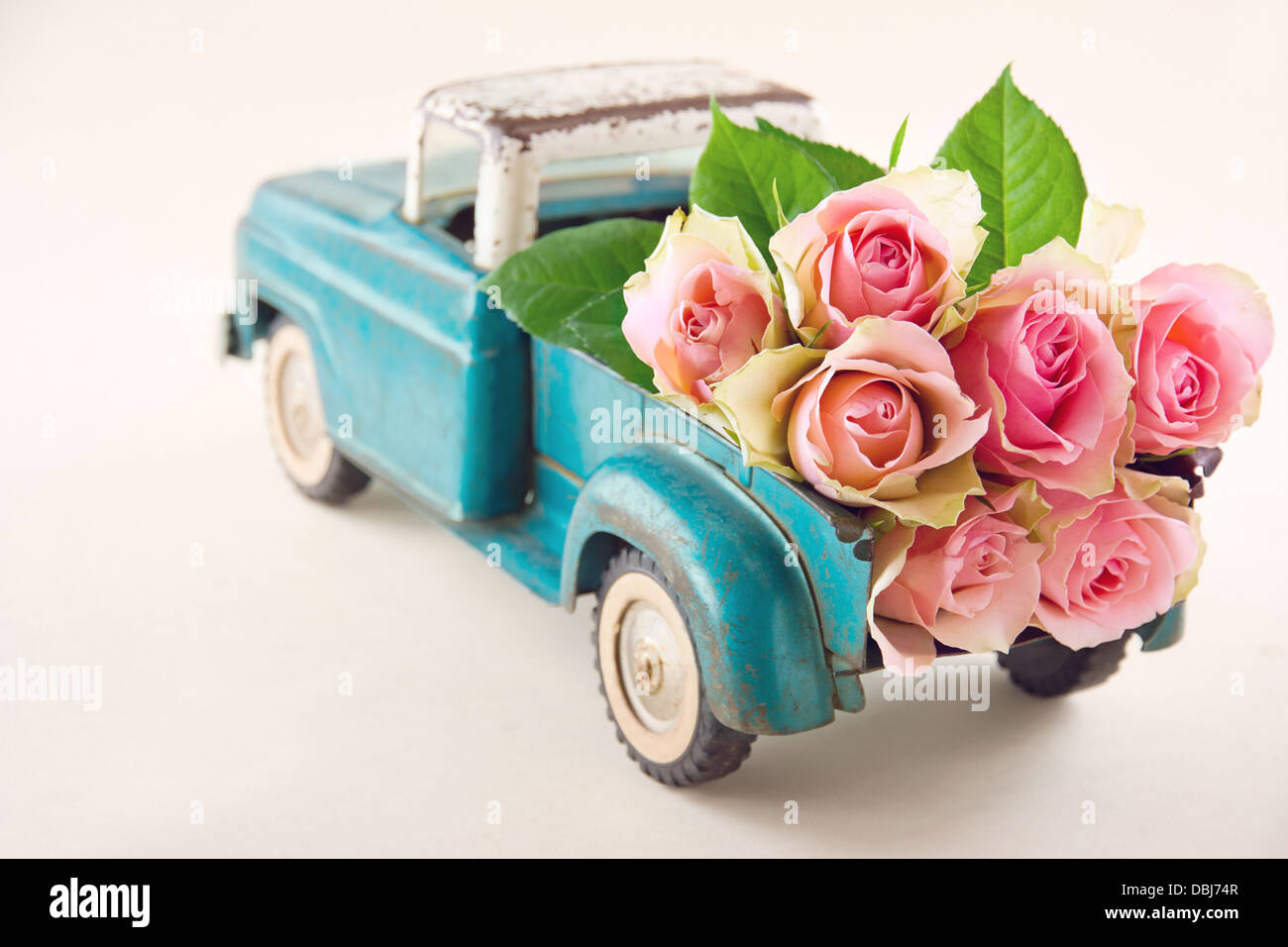 Alt antik Spielzeug-LKW tragen rosa Rosenblüten Stockfoto