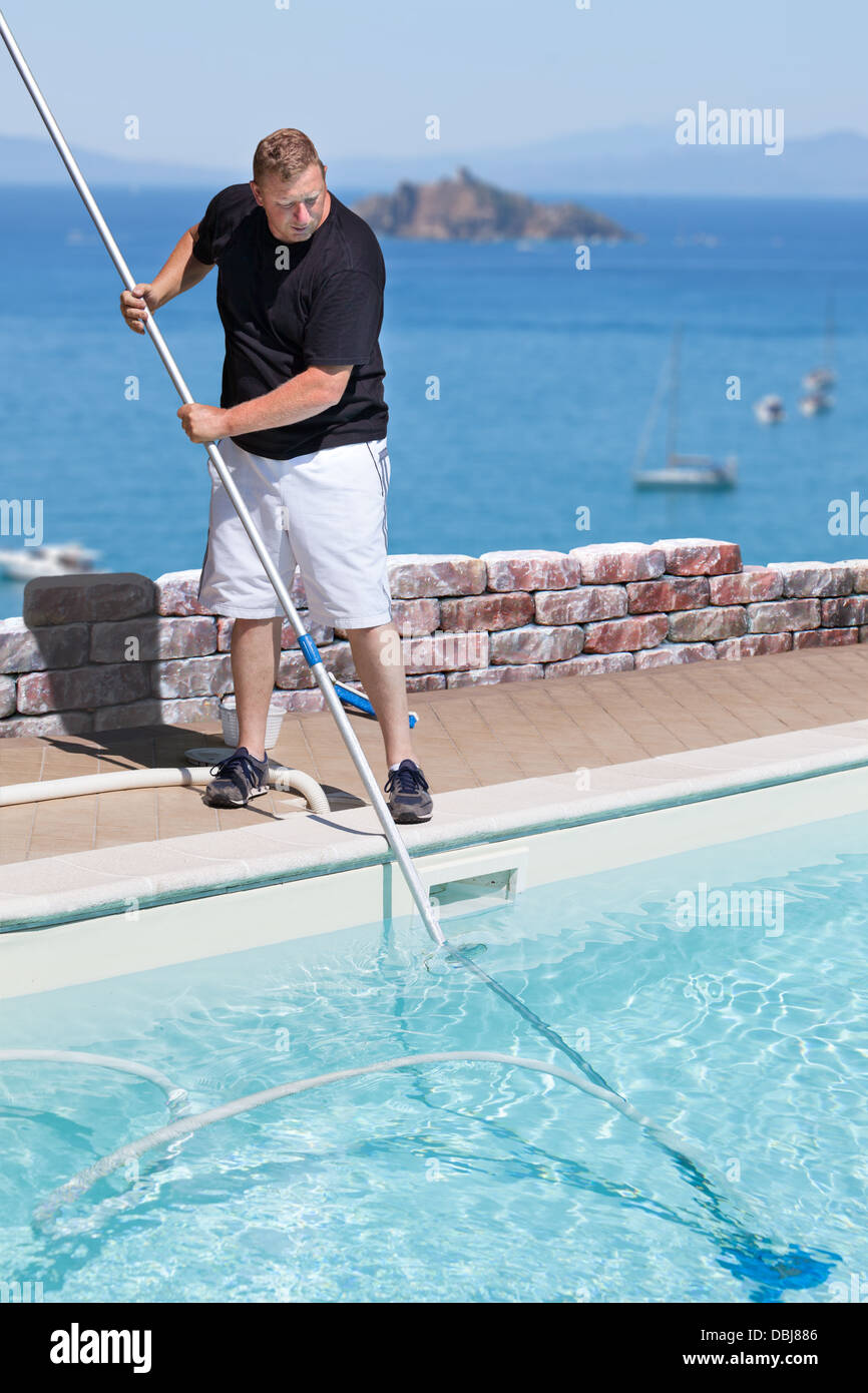 Mann, Reinigung Schwimmbad über dem Meer Stockfoto