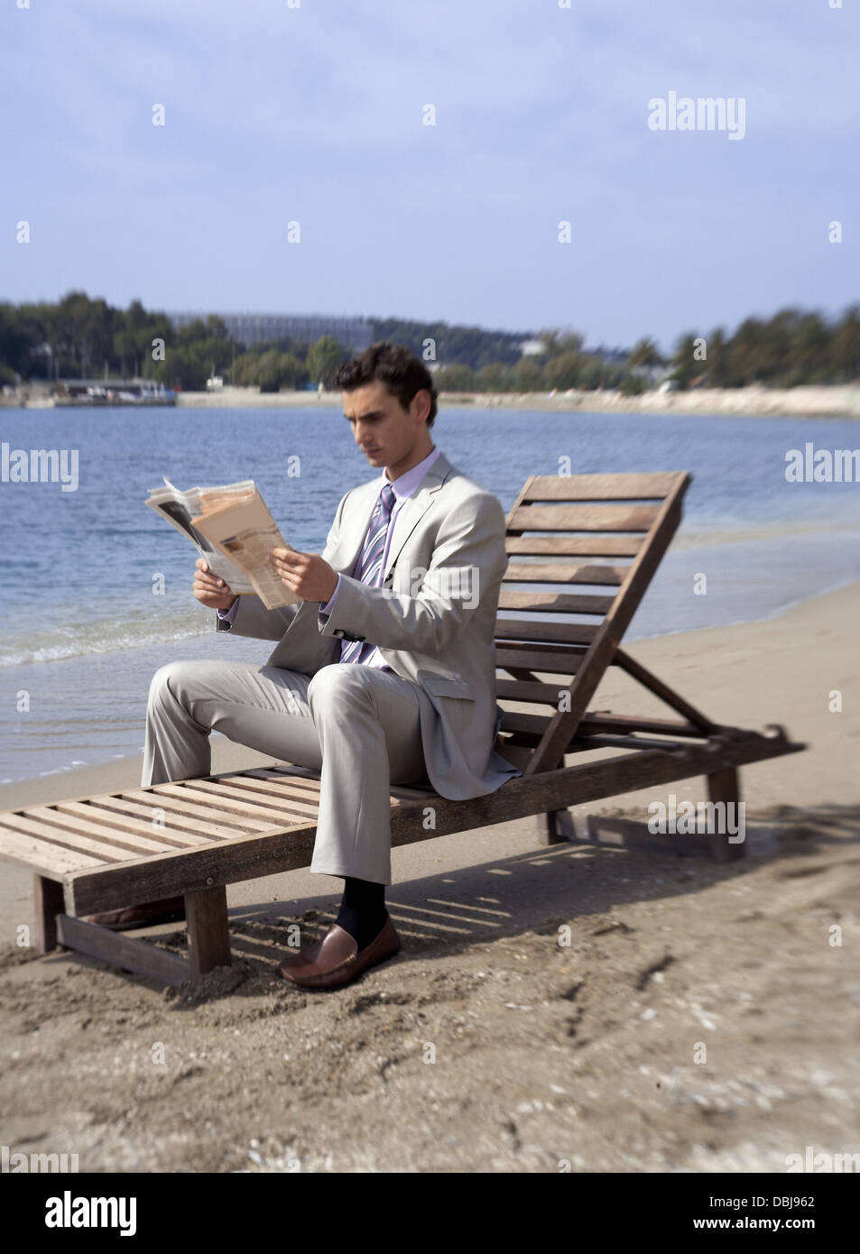 Geschäftsmann am Strand mit einer Zeitung Stockfoto