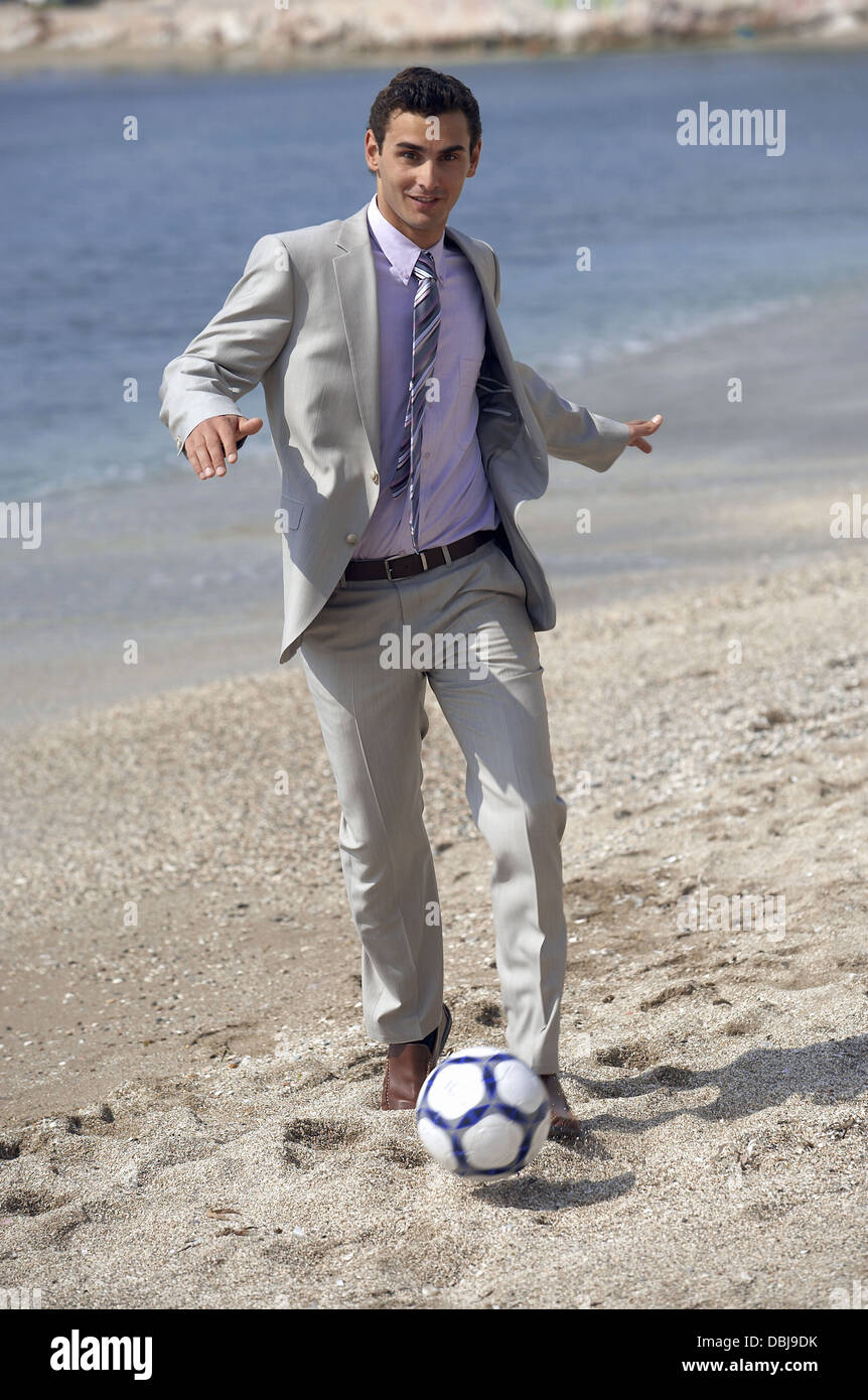 Geschäftsmann am Strand Fußball spielen Stockfoto