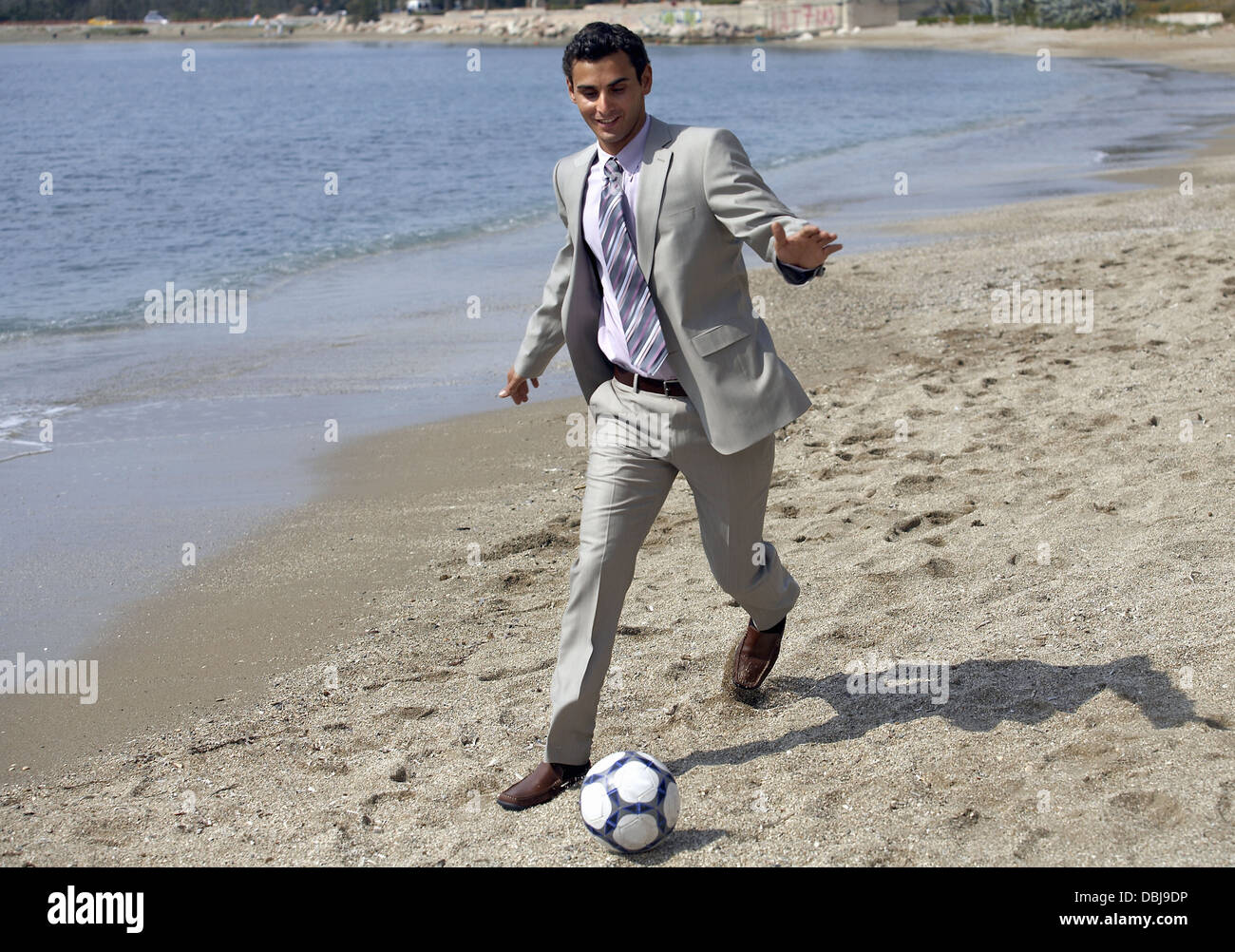 Geschäftsmann am Strand Fußball spielen Stockfoto