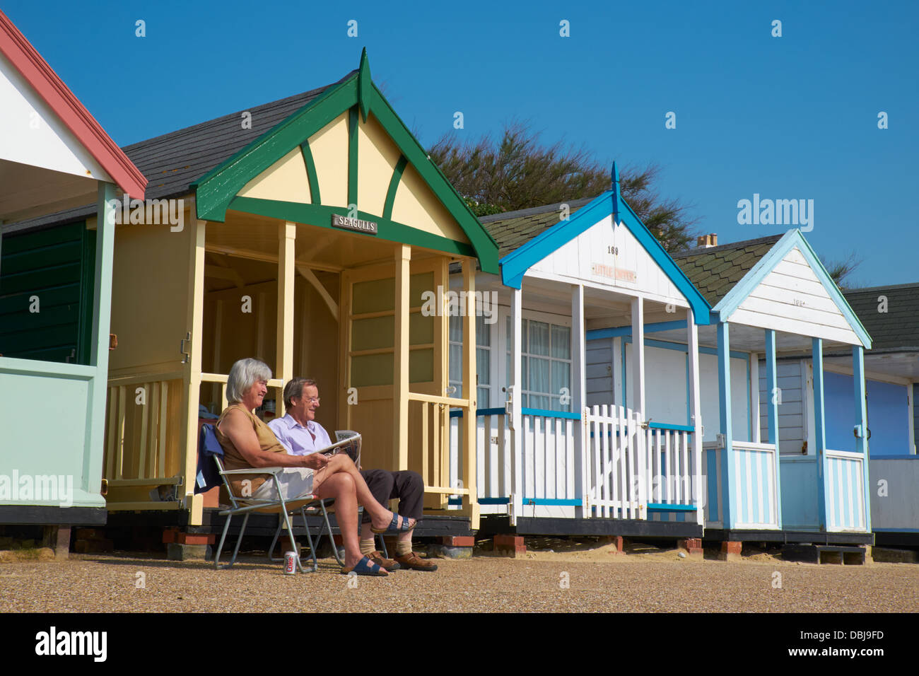 Paar mittleren Alters entspannende außerhalb ihrer Strandhütte in Southwold, Suffolk, England. Stockfoto