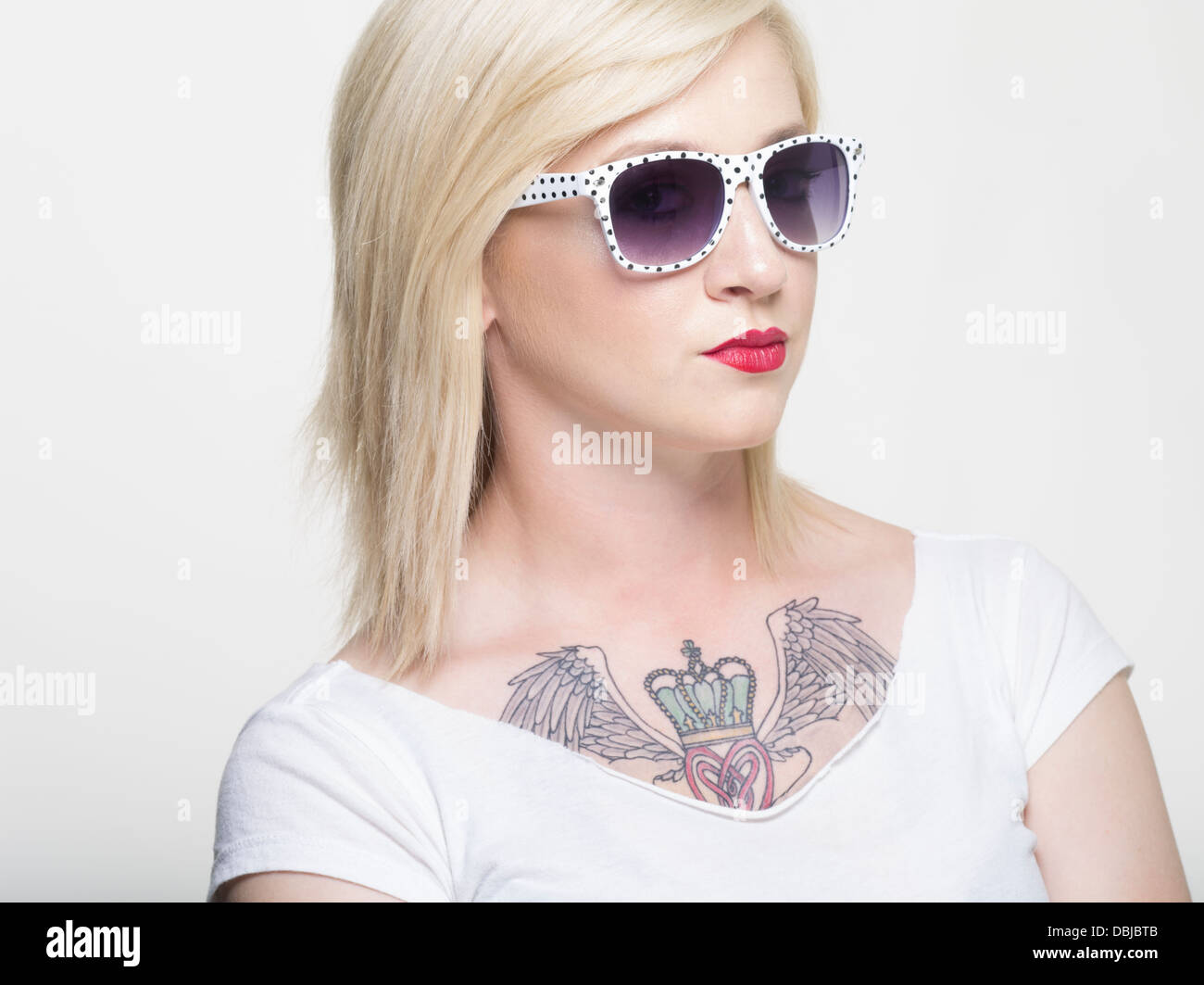 Junge, blonde Kaukasische Frau mit großen Claddagh-Tattoo auf Brust Stockfoto
