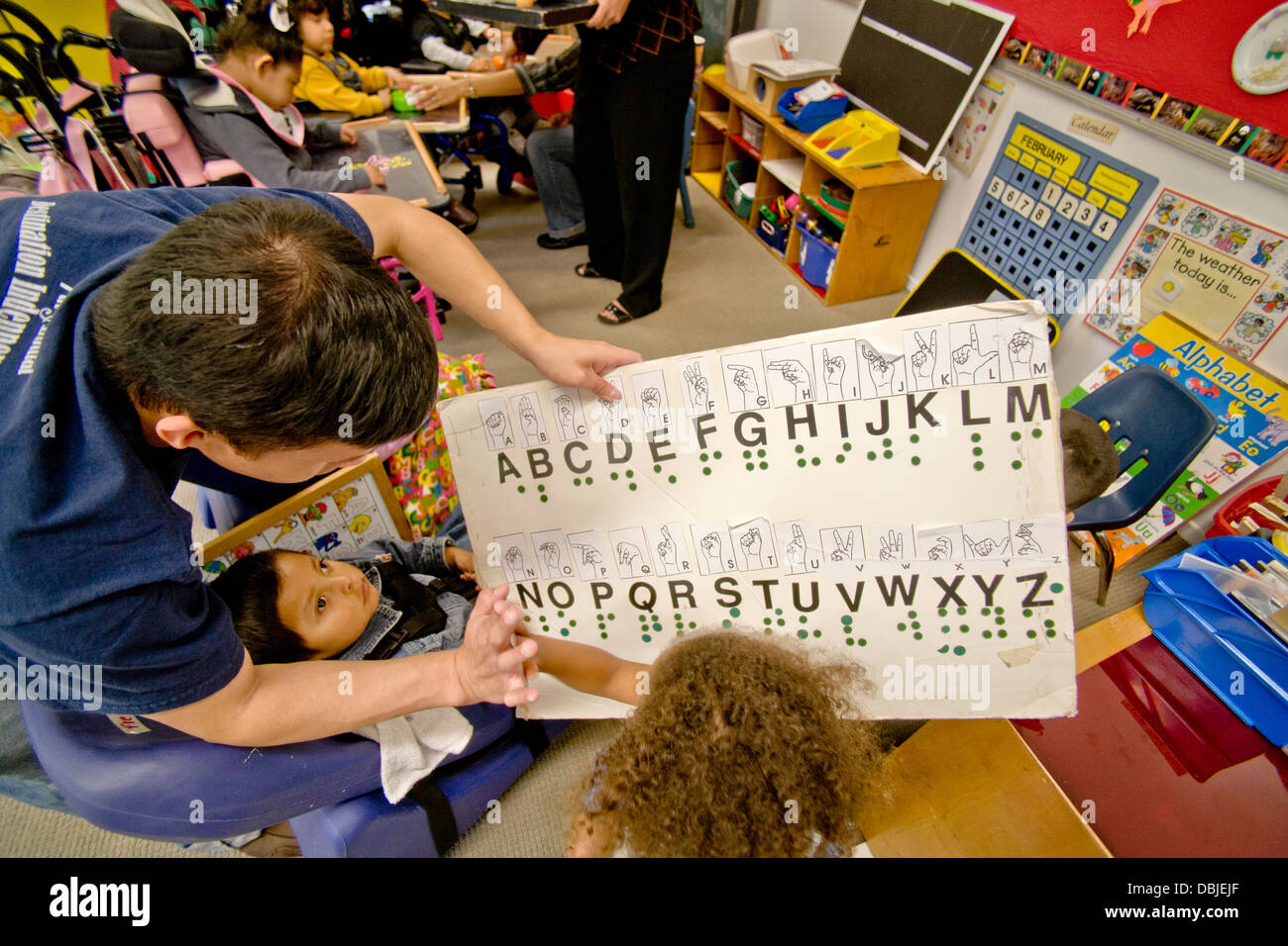Geschulte Mitarbeiter verwenden taktile Buchstaben, die Schüler spürt auf speziell bedruckten Bogen, lesen und schreiben zu lehren Stockfoto
