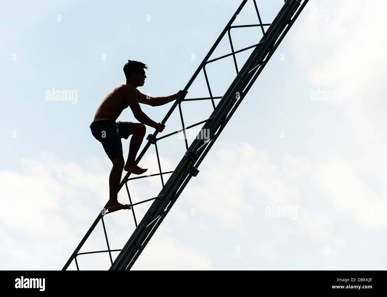 Die Silhouette eines Mannes, ein Strommast hinauf. Stockfoto