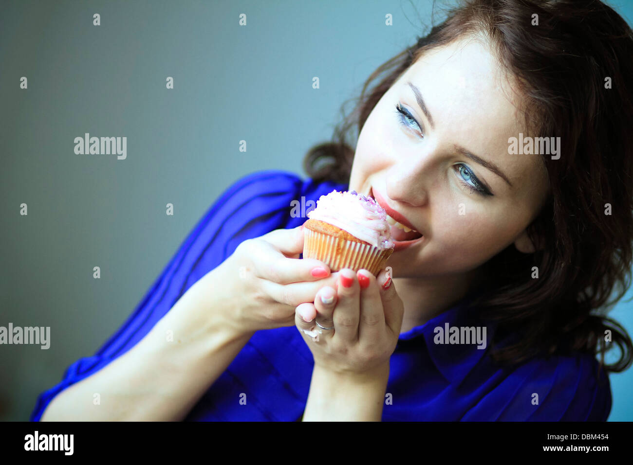 Frau mit braunen Haaren Essen einen Cupcake, Kopenhagen, Dänemark Stockfoto