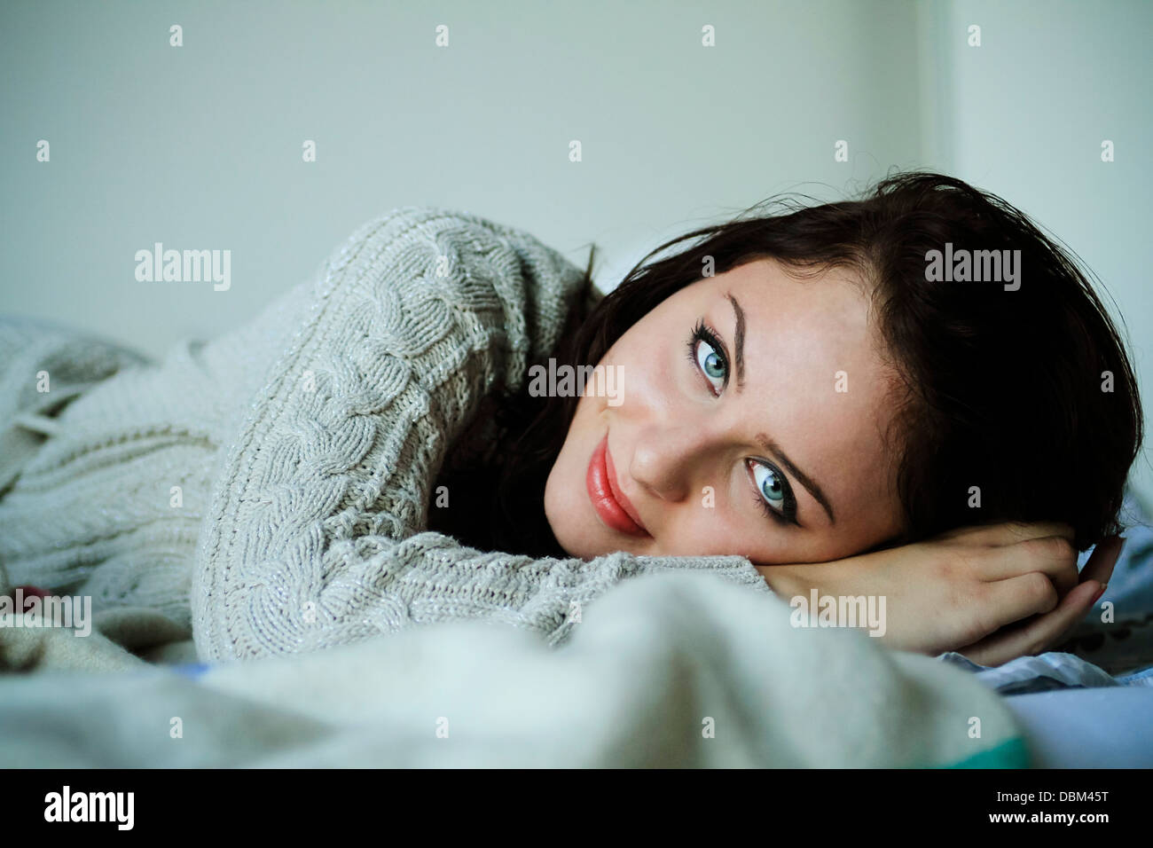 Frau mit braunen Haaren liegend auf dem Bett, Kopenhagen, Dänemark Stockfoto