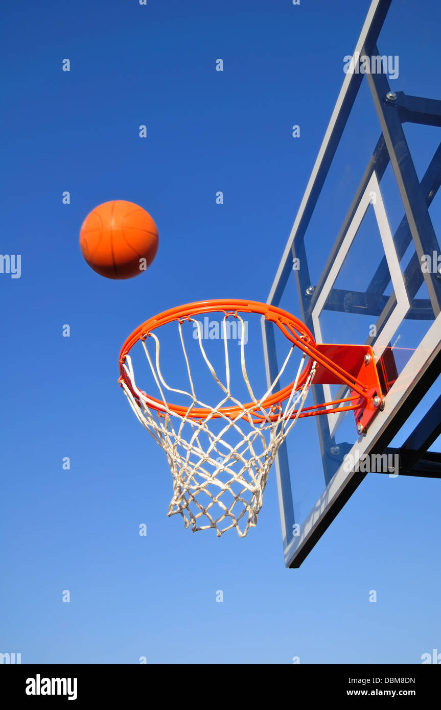 Basketballkorb vor blauem Himmel wird ball geht ins Netz Stockfoto