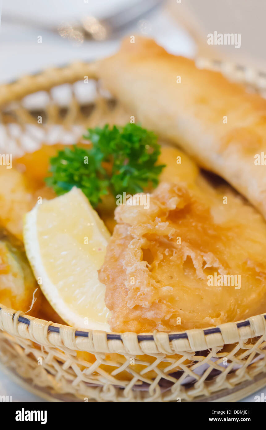 fritierter Fisch und Chips in Korb und Scheibe Zitrone Stockfoto