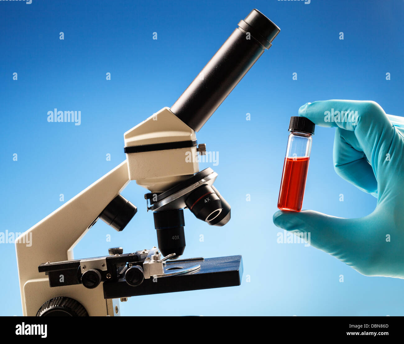 Fluid-Probe im Reagenzglas gegen ein Mikroskop Stockfoto