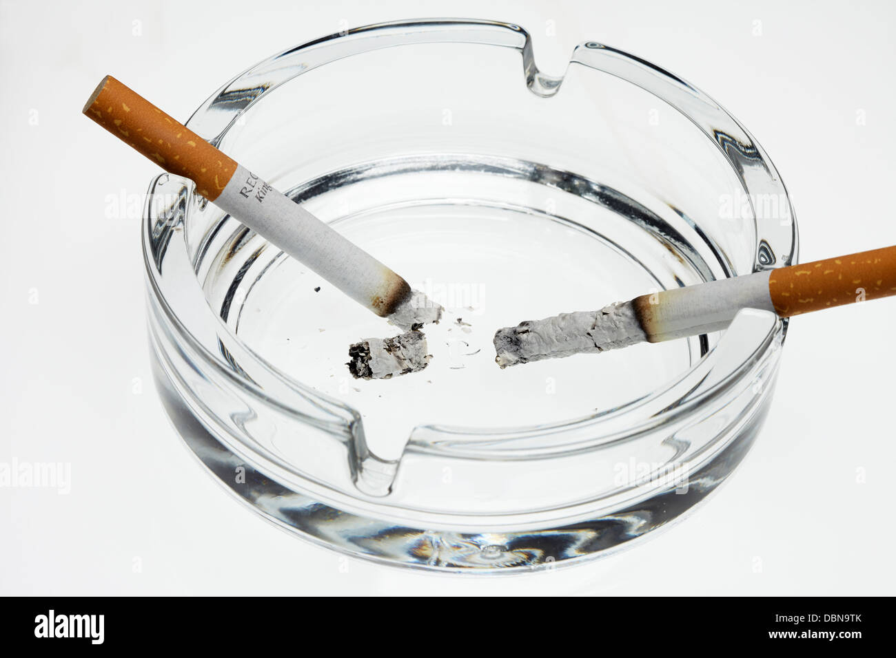 Aschenbecher und brennende Zigaretten auf weißem Hintergrund Stockfoto