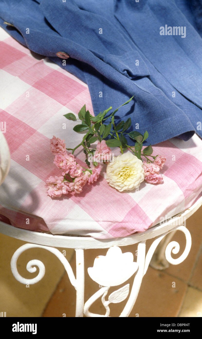 Nahaufnahme der blaue Jeansjacke und rosa aufgegebenes Kissen auf weißen Schmiedeeisen Stuhl Stockfoto
